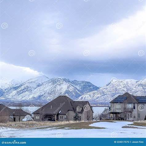 Snowy lake-front homes in Utah with a view of the Wasatch Mountains and cloudy sky