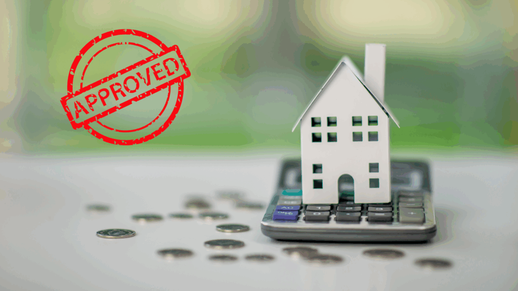 A paper house on a calculator surrounded by coins with an approved mortgage stamp