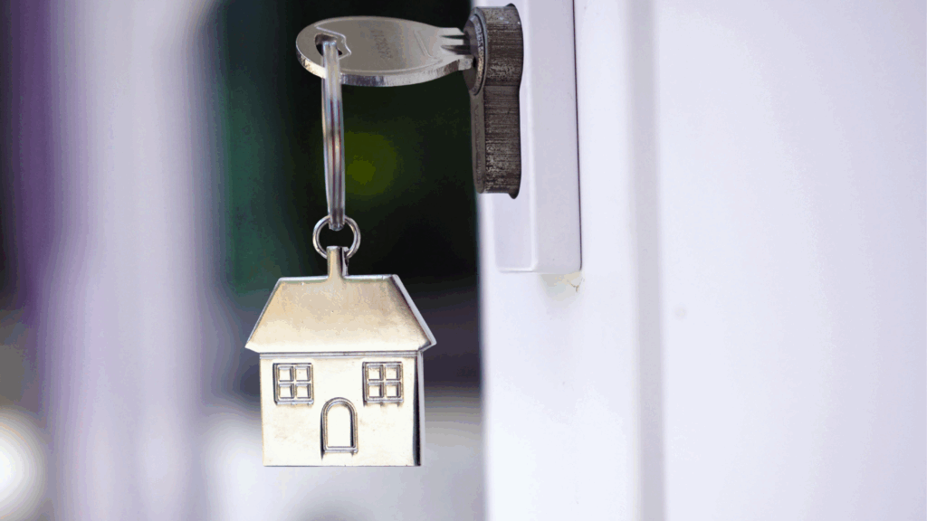 Silver house keychain hangs from a key in a lock