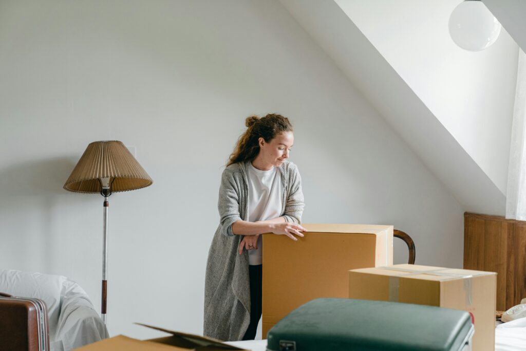 Young woman in new home with moving boxes and smiling.