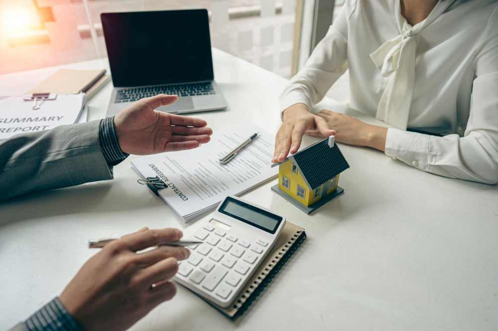 Mortgage advisor and client reviewing contract agreement and calculator — Utah home buyer loan comparison