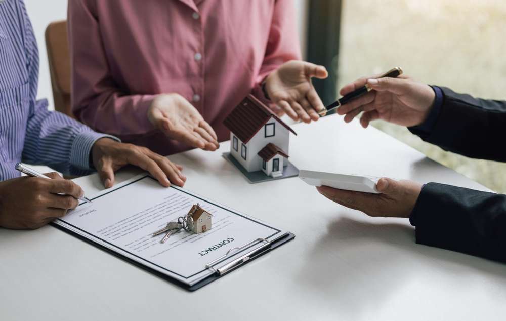 Couple reviewing home loan contract and keys with mortgage advisor — Utah mortgage pre-approval documents